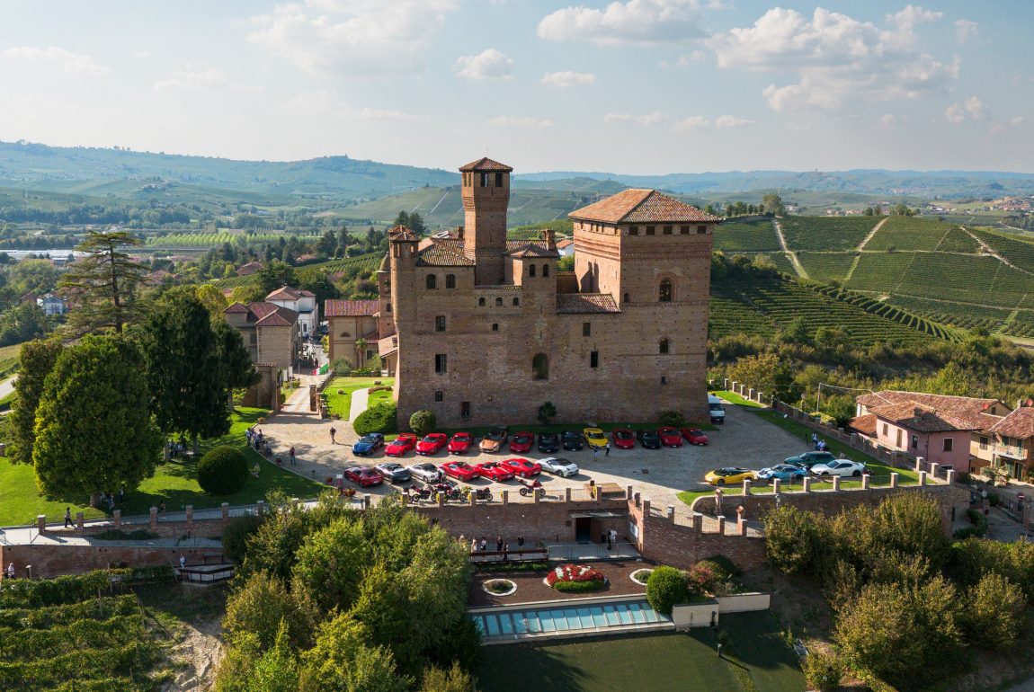Veduta aerea di un castello tra i vigneti, con le auto del raduno Autoluce in Piemonte 2026