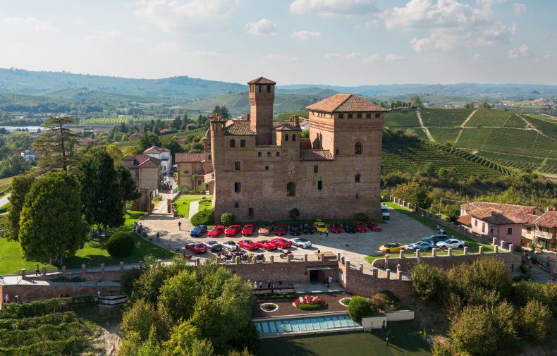 Veduta aerea di un castello tra i vigneti, con le auto del raduno Autoluce in Piemonte 2026